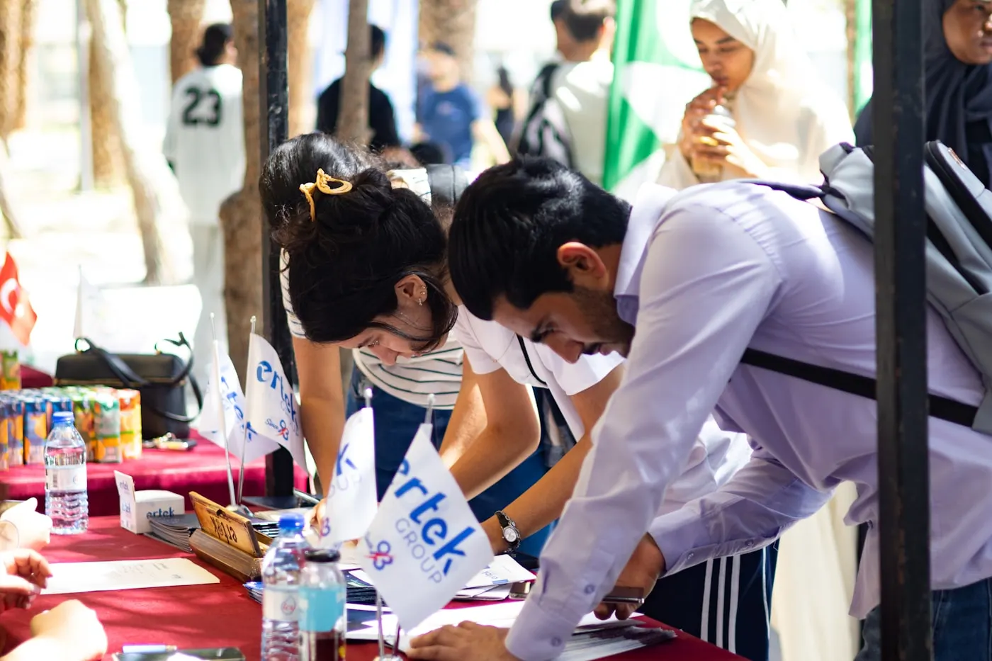 Mesa con banderas en la que varias personas firman documentos.