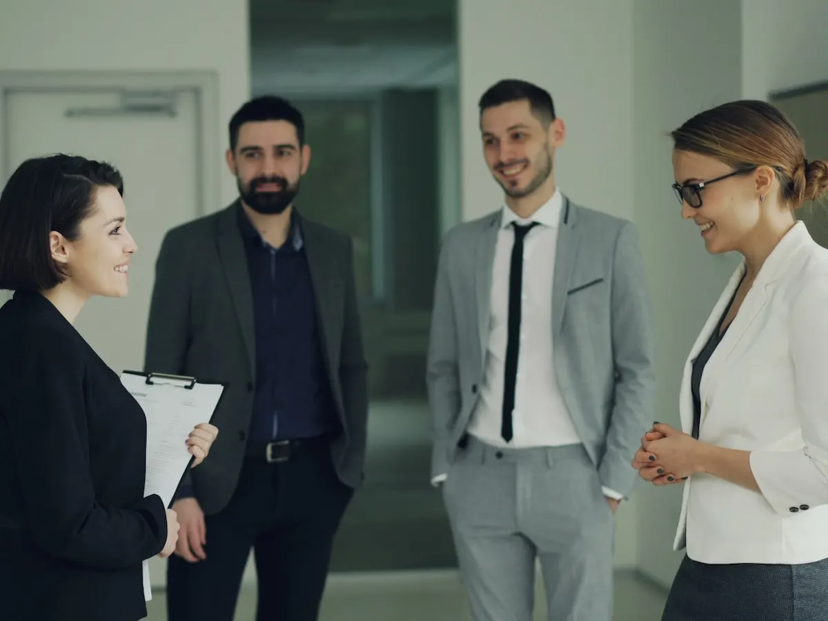 Cuatro personas con traje conversando en una oficina.