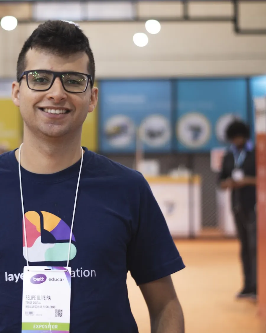 Retrato de un joven sonriente con camiseta y acreditación en un evento.